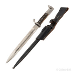 A World War II German dress bayonet with a polished blade, etched with the inscription “Zur Erinnerung an meine Dienstzeit,” decorative scrollwork, and a Wehrmacht eagle. The handle features stag horn grips, and the set includes a black-painted scabbard and leather frog.