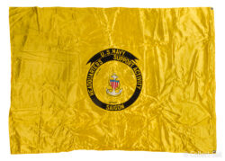 A bright yellow satin flag featuring the emblem of the U.S. Navy Headquarters Support Activity, Saigon. The emblem includes a circular black banner with gold text, encircling a shield and anchor design in red, white, and blue