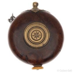 A circular powder flask from the late 18th century, possibly Russian or Eastern European. The burled walnut body features a central brass medallion with engraved patterns, a brass pouring spout with leaf-like engravings, and a bone or ivory base plug