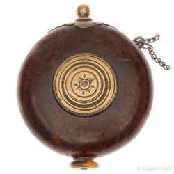 A circular powder flask from the late 18th century, possibly Russian or Eastern European. The burled walnut body features a central brass medallion with engraved patterns, a brass pouring spout with leaf-like engravings, and a bone or ivory base plug